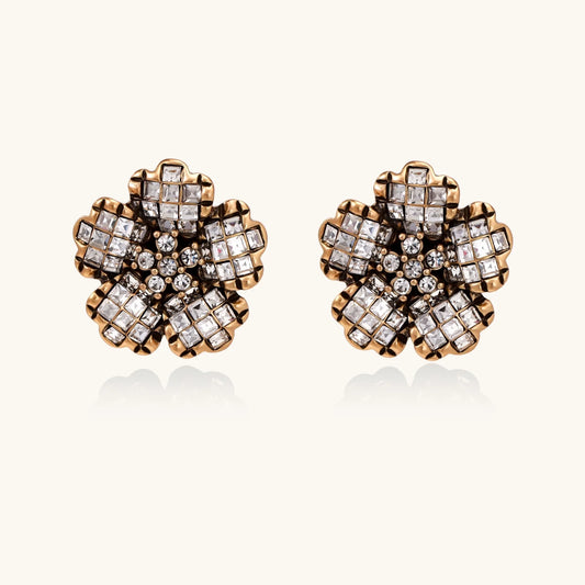 Gold-plated floral stud earrings with geometric zirconia crystals arranged in five-petal design on cream background