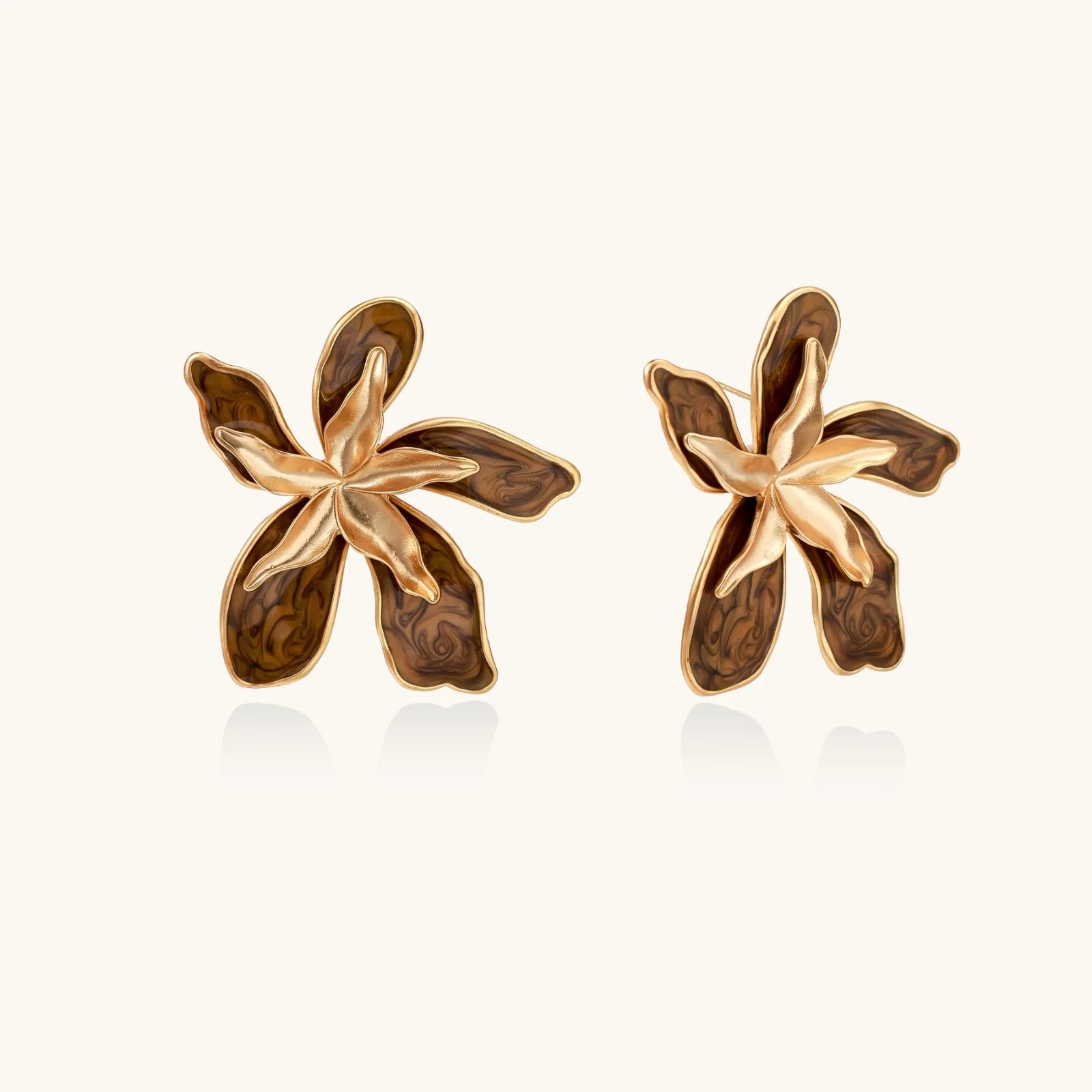Gold-plated brass flower earrings with brown tortoiseshell enamel petals on cream background