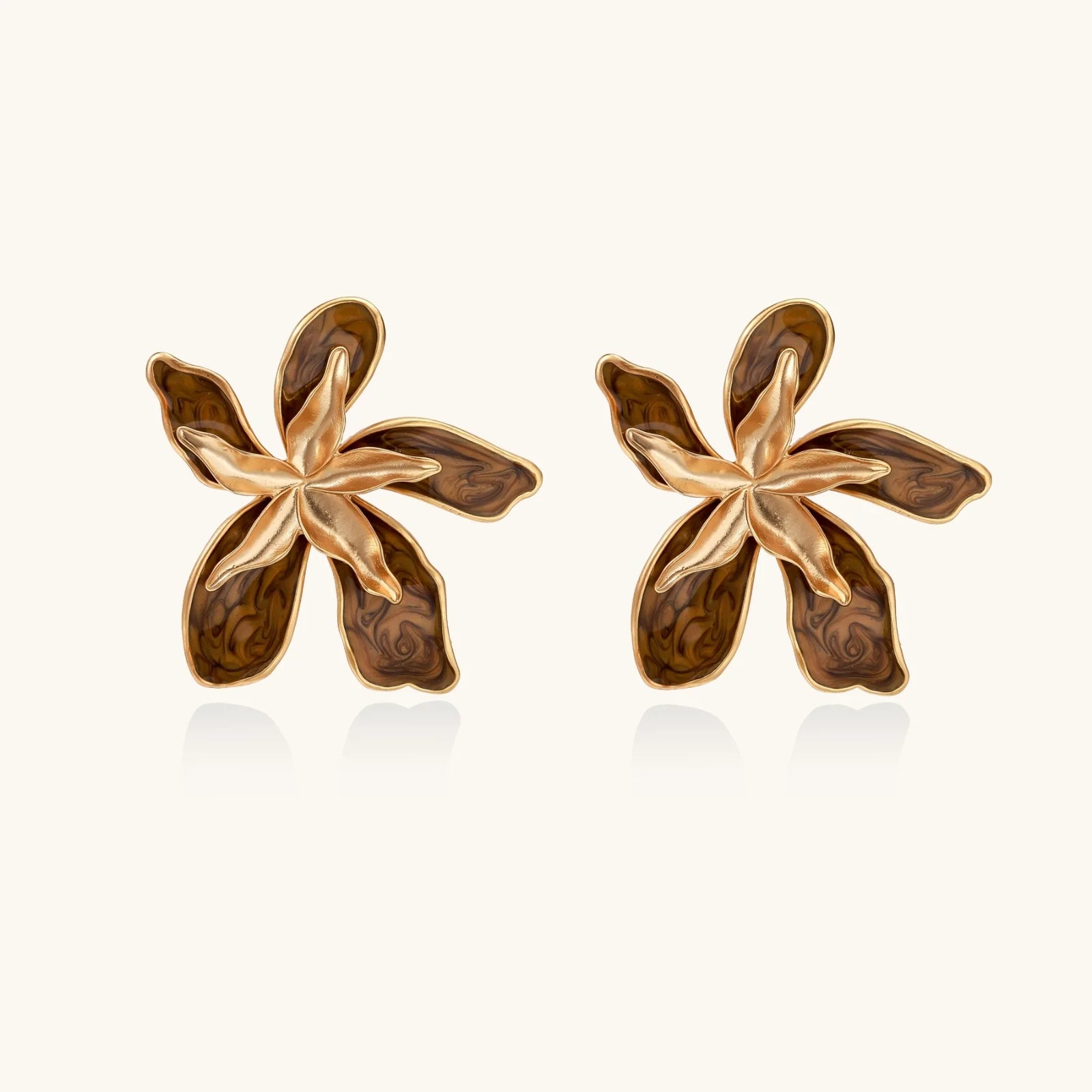 Gold-plated brass flower earrings with brown tortoiseshell enamel petals on cream background