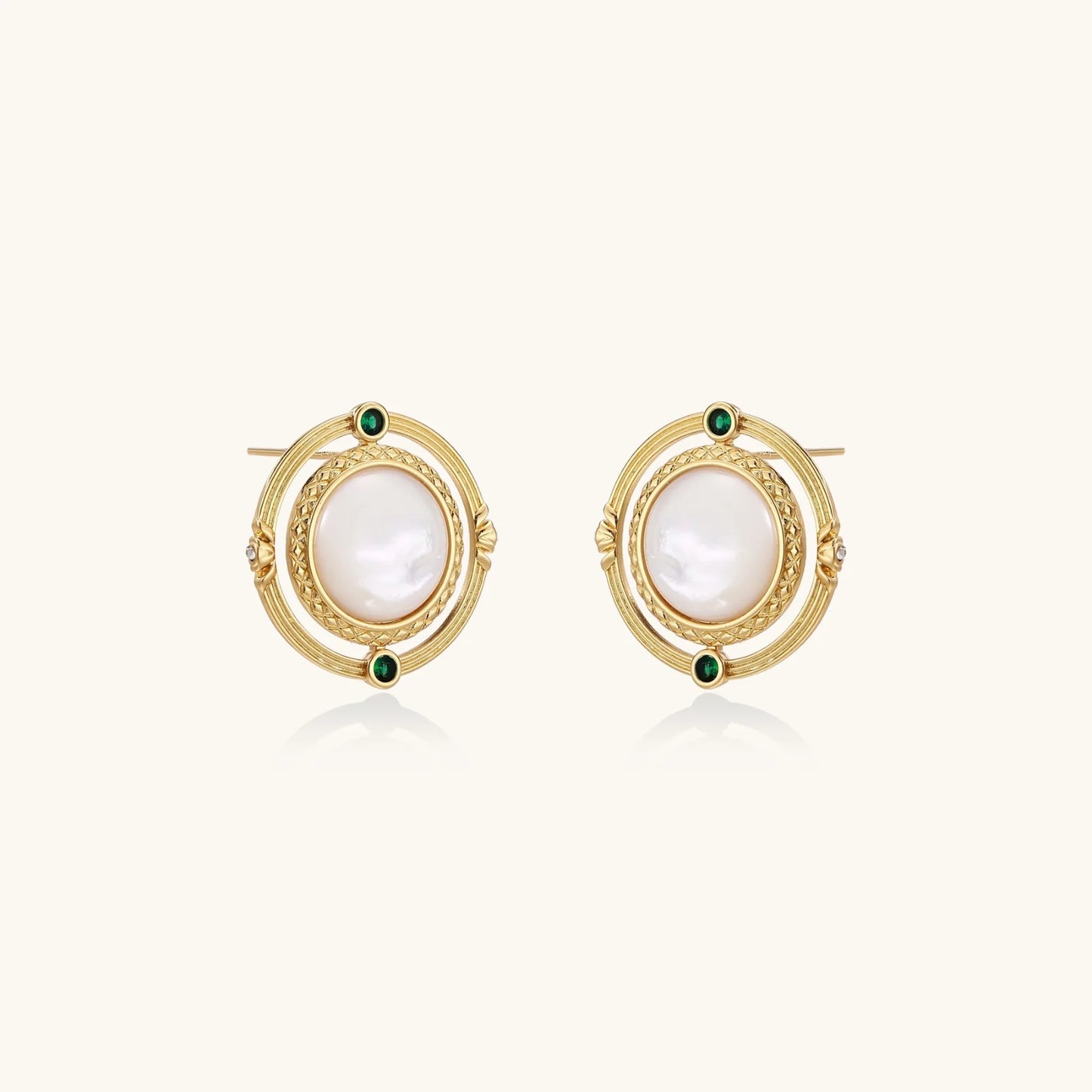 Circular gold stud earrings with iridescent mother-of-pearl center and green zirconia accents on cream background.