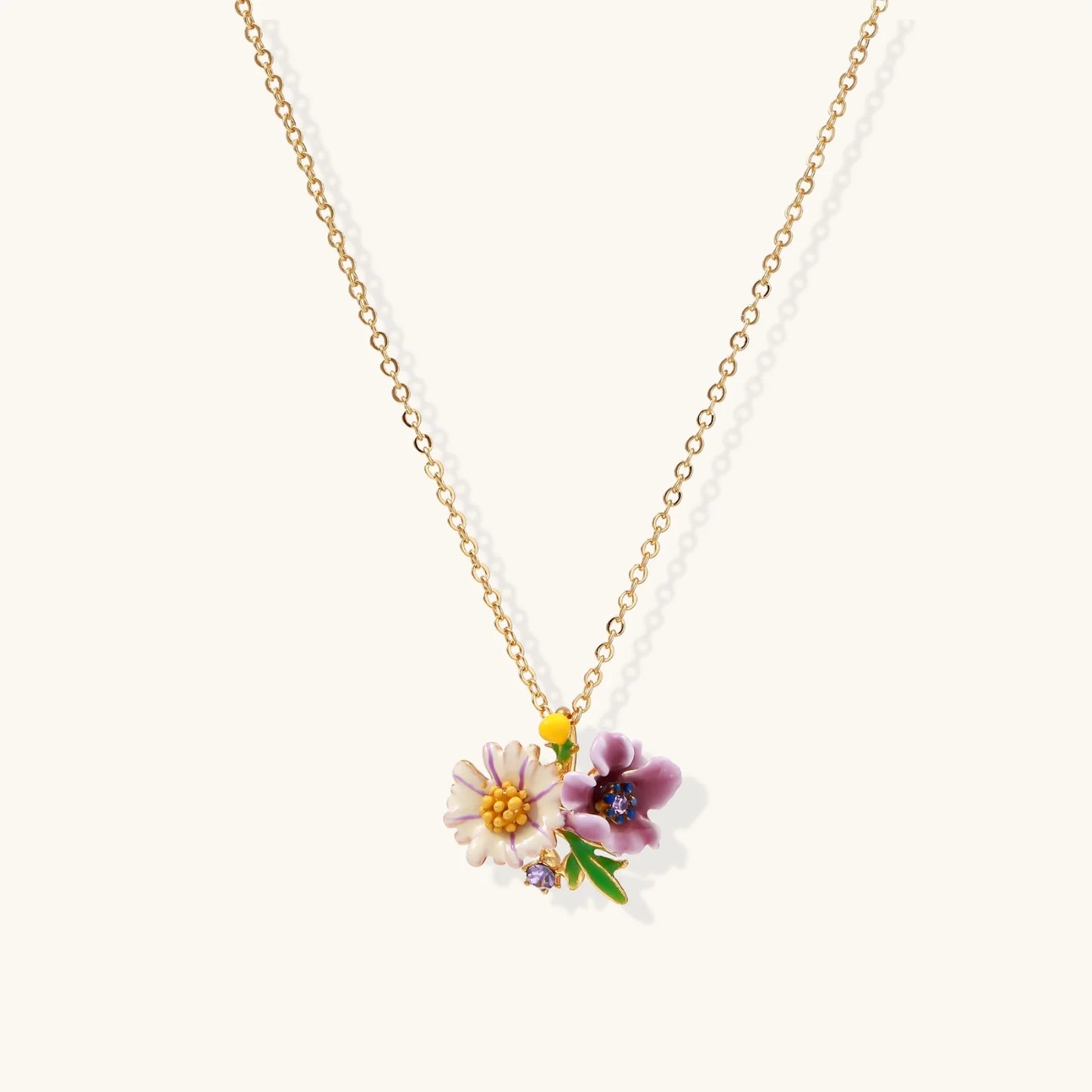 Gold-plated necklace with pink and purple enamel flower pendant featuring crystal accents on cream background
