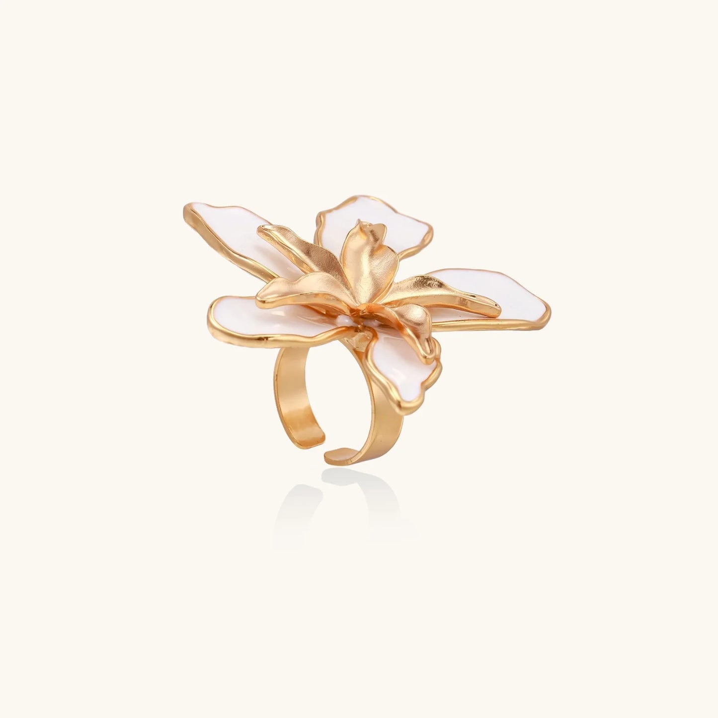 Gold-plated sculptural ring featuring white enamel petals forming an oversized lily bloom on adjustable band