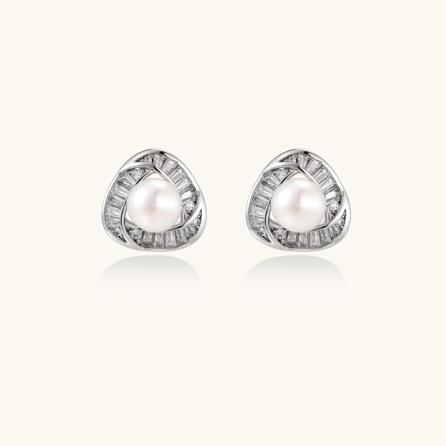 Triangular white gold plated stud earrings with central freshwater pearl and baguette-cut stones on white background