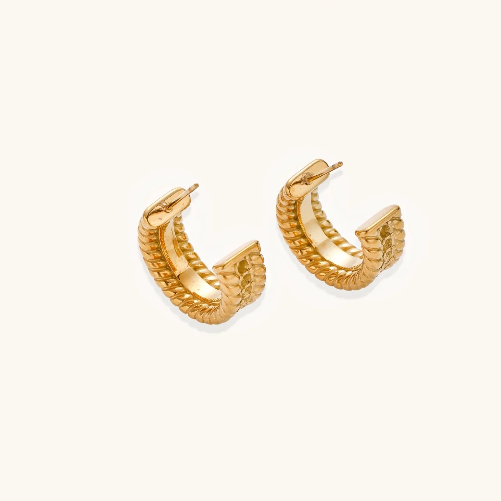 Chunky gold hoops with dimensional ridged texture and 14K plated finish shown in front and side view on cream background.
